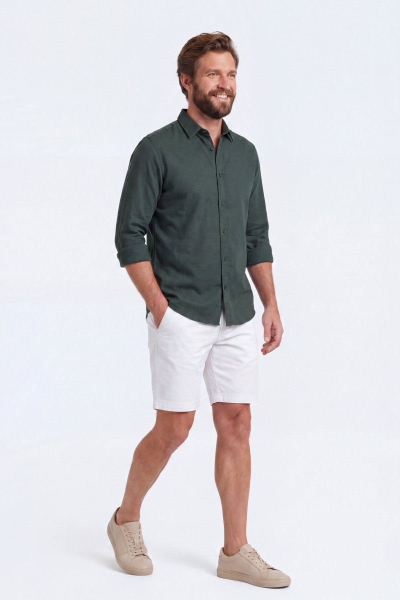 Man wearing Whitecaps * The Everydays men's shorts in white, paired with a dark green shirt, showcasing Frankster’s comfortable, versatile cotton fabric shorts.